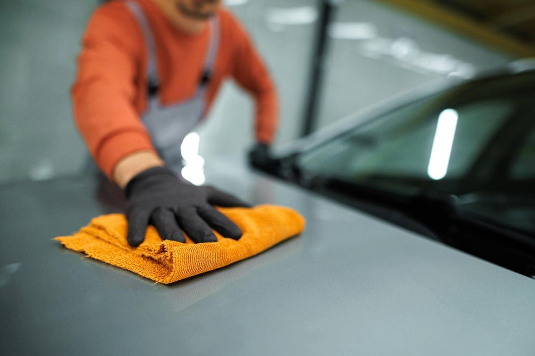 Close up shot of an unrecognizable professional car detailer cleaning car hood with microfiber towel carcarez blog image