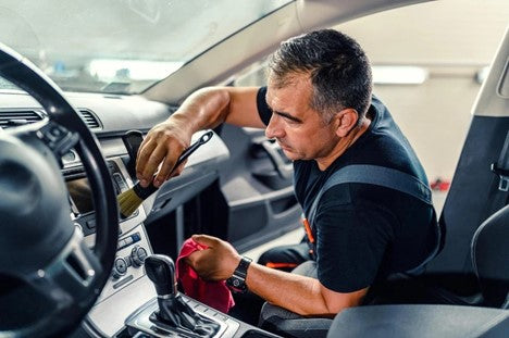 A complete dashboard CarCarez cleaning kit, including a car cleaning brush, shammy cloth, and coral fleece fabric, placed on a clean, shiny car dashboard, ready for use in maintaining its look and durability