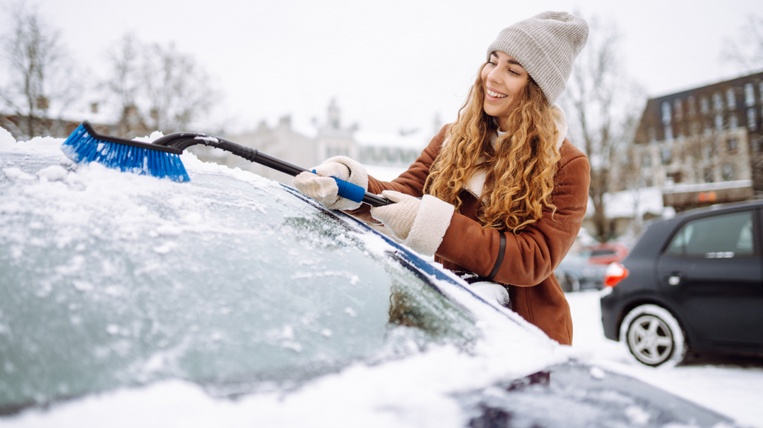 A girl removing snow from her car windshield with carcarez snow removal products