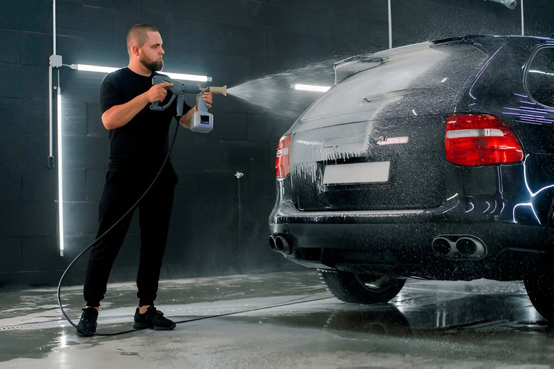 A man inside a garage uses a carcarez hand pump foam sprayer to spray foam in the liftgate of a black SUV