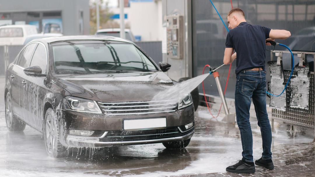 A person washing his car with jet water sprayer machine