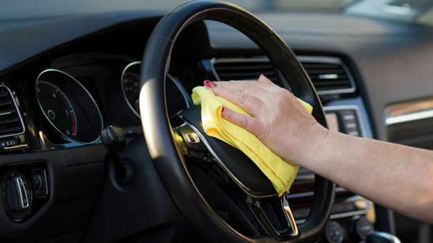 Person cleaning car steering with CarCarez Microfiber towel