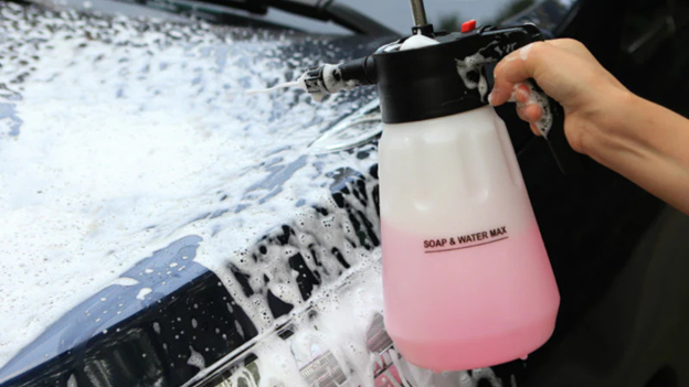 Person using Carcarez Hand Pump Foam Sprayer (1.5L) to apply thick foam on a car's surface.